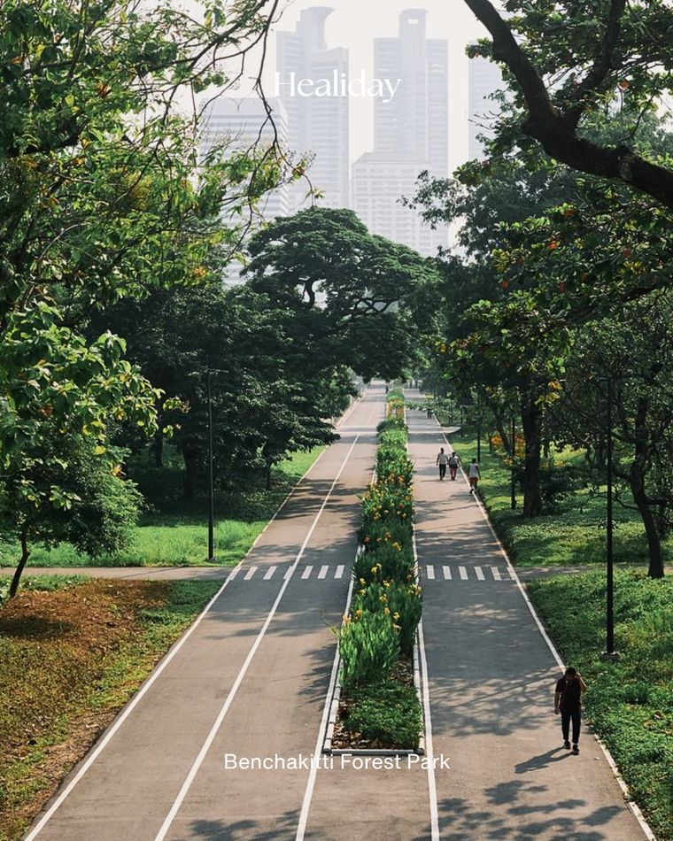 Tree-lined promenade with city skyline at Benchakitti Forest Park, Bangkok